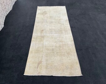 May include: A light beige vintage rug with a subtle pattern. The rug has a worn, distressed look and is made of natural fibers.