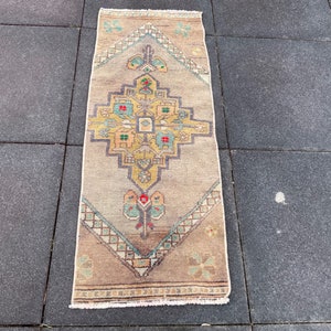 May include: A beige and brown patterned rug with a geometric design. The rug has a fringe border and is made of wool.