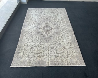 May include: A vintage-style rug with a faded floral pattern in shades of gray and white. The rug has a distressed look and is made of a soft, woven material.