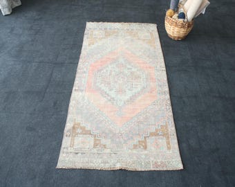 Puede incluir: Una alfombra de estilo vintage con un patrón geométrico rosa claro y marrón. La alfombra tiene un aspecto descolorido y está hecha de un material suave y tejido.
