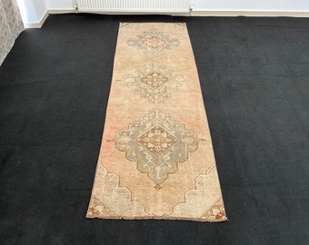 Op de afbeelding: Een vintage loper met een beige achtergrond en een herhalend patroon van lichtblauwe en bruine ruiten.
