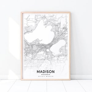 Puede incluir: Una impresión de mapa en blanco y negro de Madison, Wisconsin. El mapa muestra las calles de la ciudad, los lagos y otras características geográficas. El texto "MADISON WISCONSIN 43°4' 6" N 89° 24' 0" W" está impreso en la parte inferior del mapa.