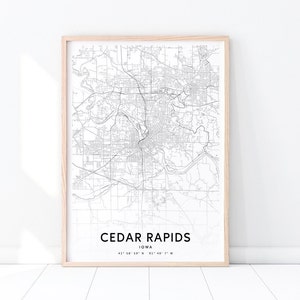 May include: A black and white map of Cedar Rapids, Iowa, with the city name and coordinates printed below. The map is framed in a light wood frame.