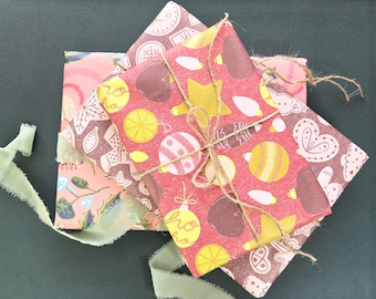 Könnte beinhalten: Drei rechteckige Geschenke in gemustertem Papier. Das oberste Geschenk ist in rotes Papier mit gelben und weißen Weihnachtskugeln und dem Text ho ho eingewickelt und mit brauner Schnur gebunden. Die anderen Geschenke haben festliche Muster.