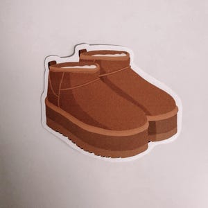 May include: A pair of brown ankle boots with a thick platform sole and a white interior lining. The boots feature a suede-like texture, a rounded toe, and a small pull tab at the back of the heel, presented as a die-cut sticker design.