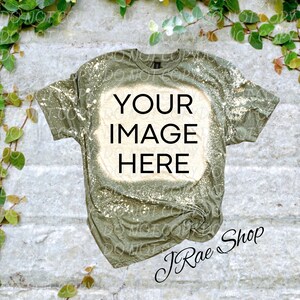 May include: A green t-shirt with a bleached design. The shirt has the text "YOUR IMAGE HERE" in a white box on the front. The shirt is lying flat on a textured surface.