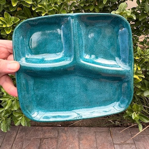 May include: A teal blue ceramic divided serving dish with three sections. The dish has a speckled glaze and a glossy finish.