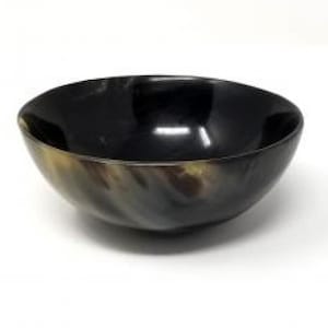 Puede incluir: Un cuenco marrón oscuro brillante con un diseño liso y curvado. El cuenco tiene un aspecto natural veteado con tonos marrón claro y beige cerca del borde. El interior es negro profundo y reflectante.