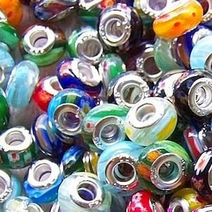 May include: A selection of vibrant glass beads with silver metal cores. The beads display diverse patterns, such as swirls and floral designs, alongside solid colours. The colour scheme includes blues, greens, yellows, oranges, and reds. These beads are likely for jewellery making.