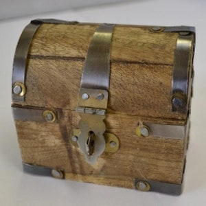 Könnte beinhalten: Eine kleine Holzkiste mit Metallverzierungen, Scharnieren und einem Schloss. Die Kiste ist braun mit einer natürlichen Holzmaserung.