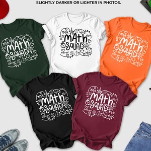 May include: A collection of t-shirts in various colors, including forest green, white, orange, black, and maroon. Each shirt features the text "MATH SQUAD" in a white, whimsical font, surrounded by decorative elements. A red baseball cap, sunglasses, and jeans are also present.