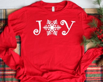 May include: Red long-sleeved shirt with a white snowflake and the word "JOY" printed on the front.