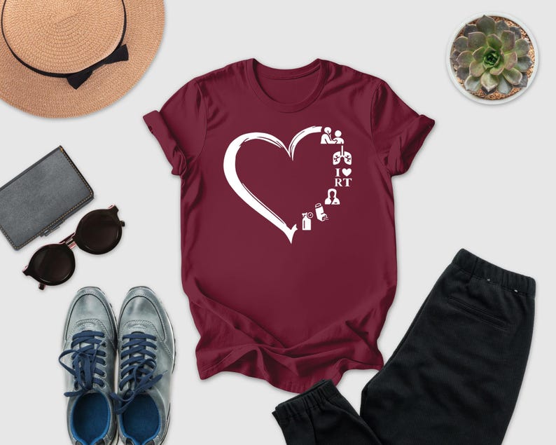 a casual outfit consisting of a burgundy t-shirt with a white heart design, a pair of gray sneakers, a pair of black pants, sunglasses, a hat, and a small potted succulent plant.
