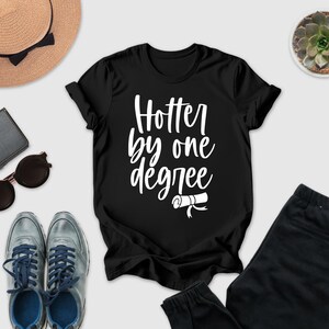 a casual outfit consisting of a black t-shirt with a white text design, a pair of sunglasses, a hat, a wallet, a pair of shoes, and a potted succulent plant.