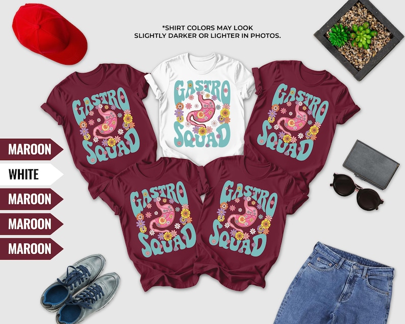 a collection of clothing items, including maroon t-shirts with the word "Gastro Squad" printed on them, a pair of jeans, a red baseball cap, sunglasses, and a small plant.