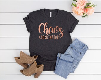 May include: A dark gray t-shirt with the text "Chaos Coordinator" in rose gold lettering.