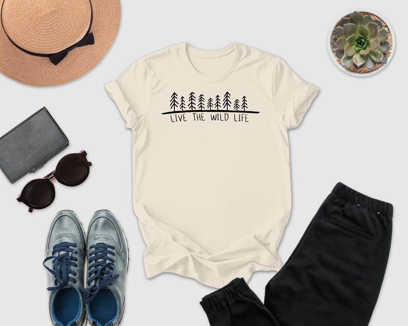 a casual outfit consisting of a white t-shirt with a graphic design, a pair of sunglasses, a hat, a wallet, a pair of sneakers, and a potted succulent plant.
