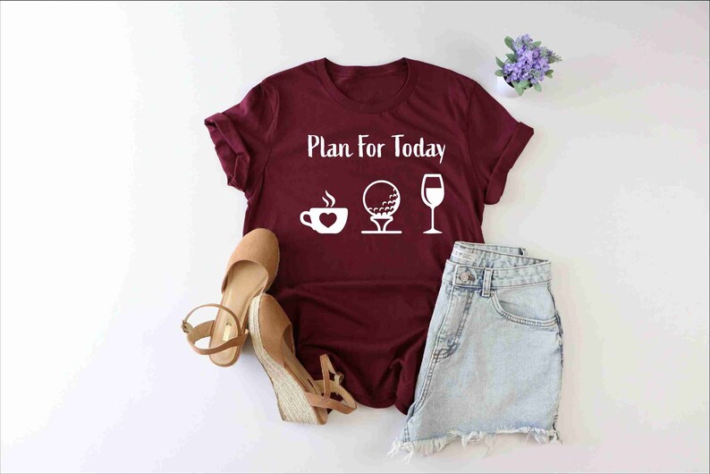 Peut inclure: Un t-shirt bordeaux avec le texte "Plan for Today" et des ic&ocirc;nes blanches d'une tasse de caf&eacute;, d'une balle de golf et d'un verre &agrave; vin.