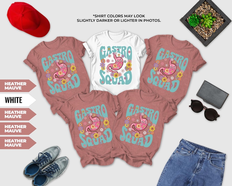 a collection of clothing items, including a white t-shirt with a pink and blue design, a pair of pink t-shirts with a similar design, and a pair of jeans. There are also a red hat, sunglasses, and a potted plant in the background.