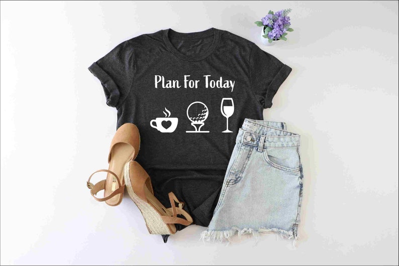 Peut inclure: Un t-shirt gris fonc&eacute; avec le texte "Plan for Today" et des ic&ocirc;nes blanches d'une tasse de caf&eacute;, d'une balle de golf sur un tee et d'un verre &agrave; vin.