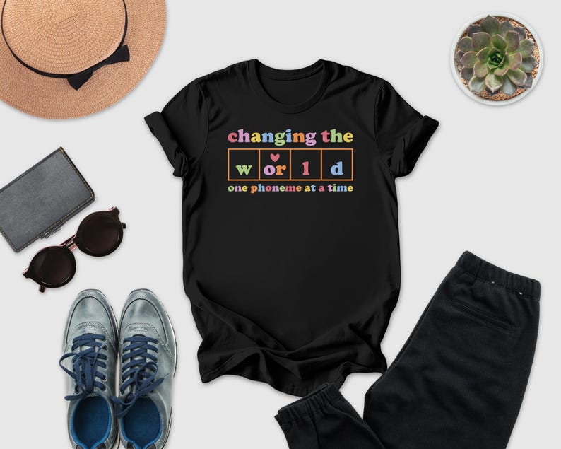 a casual outfit consisting of a black t-shirt with a colorful graphic, a pair of sunglasses, a hat, a wallet, a pair of shoes, and a potted plant.