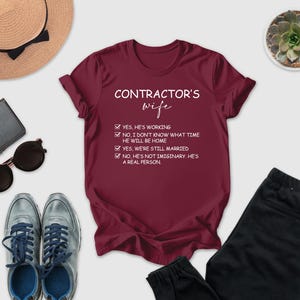 a variety of items, including a red t-shirt with a humorous text, sunglasses, a hat, a wallet, a potted plant, and a pair of pants, all arranged on a white background.