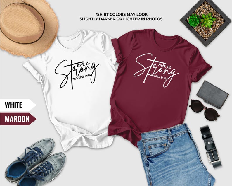 a pair of white and maroon t-shirts with the text "She is Strong" printed on them, along with a pair of jeans, sunglasses, a hat, and a wallet. The text "SHIRT COLORS MAY LOOK SLICTER OR Lighter IN PHOTOS" is also present, suggesting that the colors of the shirts may appear slightly different in photos.
