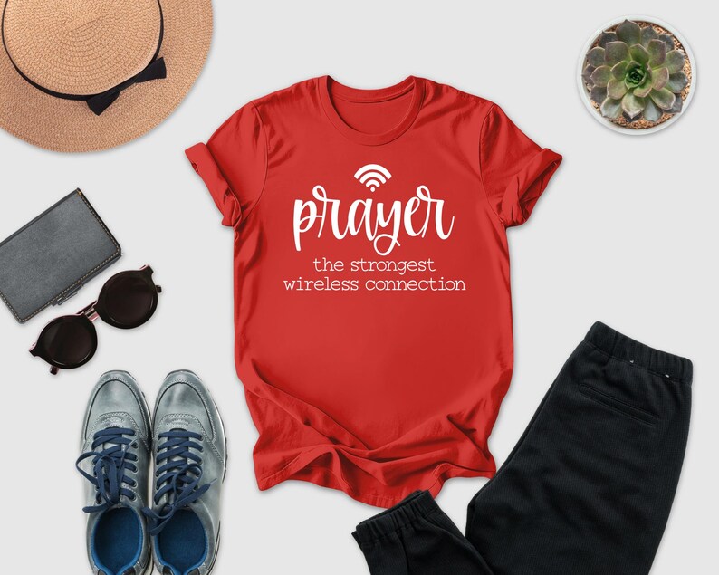 a red t-shirt with the text " Prayer the strongest wireless connection" printed on it, along with a pair of sunglasses, a hat, a wallet, and a potted succulent plant.