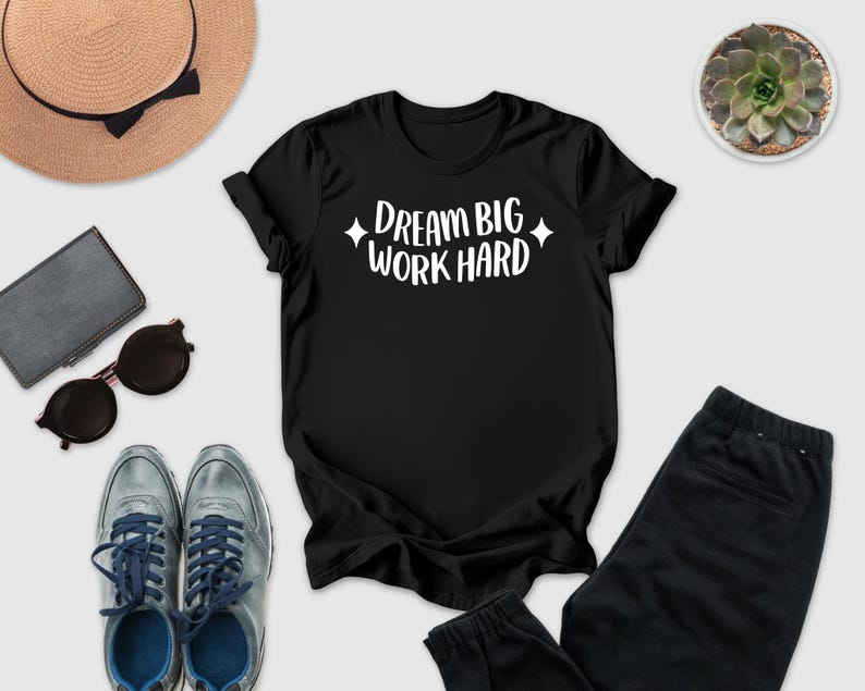 a casual outfit consisting of a black t-shirt with the text "DREAM BIG WORK HARD" printed on it, a pair of gray sneakers, a pair of sunglasses, a hat, and a potted succulent plant.