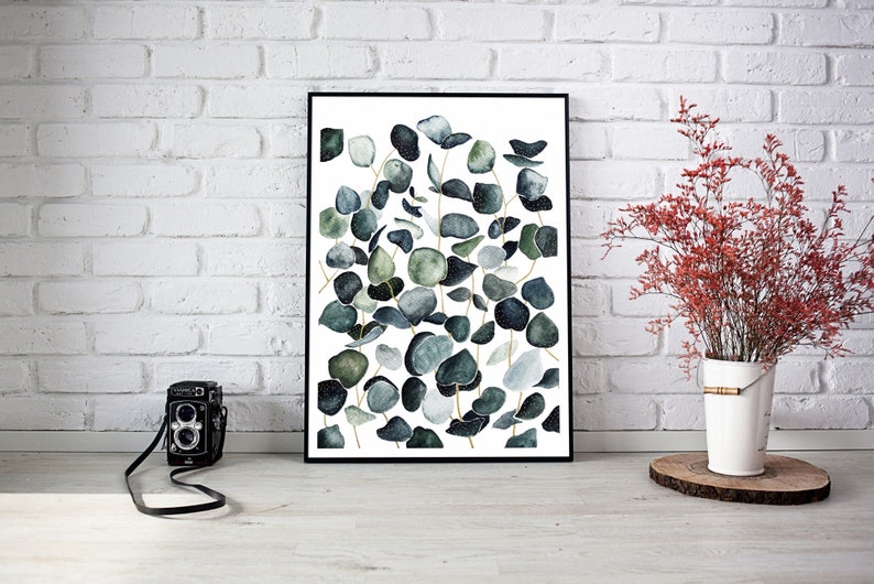 May include: A framed print of a watercolor painting featuring a cluster of eucalyptus leaves in shades of green and blue against a white background.