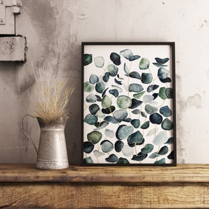May include: A framed watercolor print featuring a botanical illustration of eucalyptus leaves in shades of green and blue on a white background.