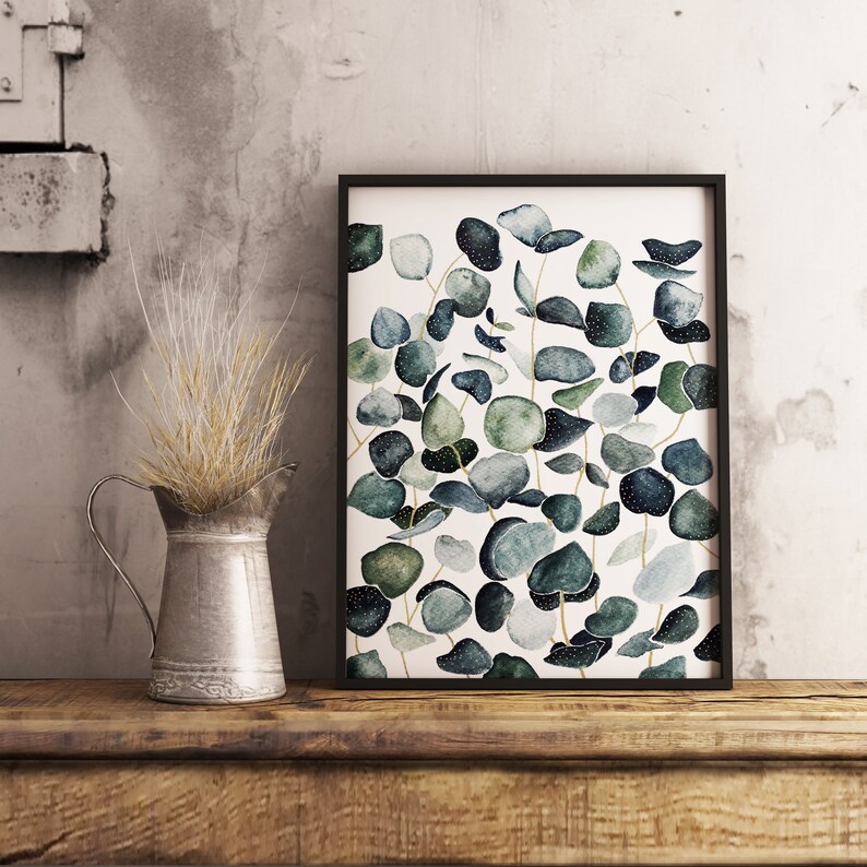 May include: A framed watercolor print featuring a botanical illustration of eucalyptus leaves in shades of green and blue on a white background.