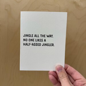 May include: A white card with black text that reads "Jingle all the way. No one likes a half-assed jingler."