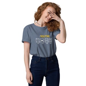 May include: A woman wearing a blue t-shirt with a graphic that says "ROUTINE" and has icons for eat, sleep, code, and repeat. The icons are in white and the text is in yellow.