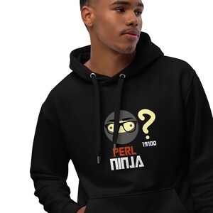 Peut inclure: Sweat-shirt à capuche noir avec un graphique représentant un ninja de dessin animé portant des lunettes et un point d'interrogation au-dessus de sa tête. Le texte "PERL NINJA" est sous le graphique, avec le numéro "19100" à droite du point d'interrogation.