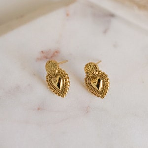 Puede incluir: Un par de pendientes de corazón de oro con un diseño detallado y texturizado.
