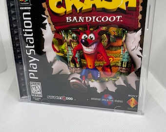 May include: A PlayStation game case for Crash Bandicoot, featuring a cartoon bandicoot character in a red and white outfit. The case is black with a red and white title and a blue and white PlayStation logo. The game is rated "K-A" for Kids to Adults by the ESRB.