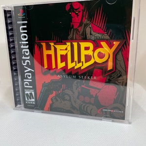 Op de afbeelding: Een PlayStation-gamecase voor Hellboy: Asylum Seeker. De cover toont een roodhuidige figuur met hoorns en een pistool. De game is door de ESRB met M voor Mature beoordeeld. De game wordt uitgegeven door Dreamcatcher.