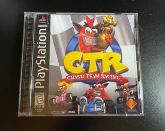 May include: A PlayStation game case for Crash Team Racing, featuring a red, white, and blue checkered background. The game's title, "CTR Crash Team Racing", is displayed in large, yellow letters. The cover art features Crash Bandicoot, a cartoon bandicoot, holding a trophy. The game is rated "E" for Everyone by the ESRB.