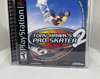 May include: A PlayStation game case for Tony Hawk's Pro Skater 2, featuring a skateboarder performing a trick in front of a bright orange and yellow background. The game features a variety of professional skateboarders, including Tony Hawk, Bucky Lasek, and Elissa Steamer. The game is rated T for Teen by the ESRB.
