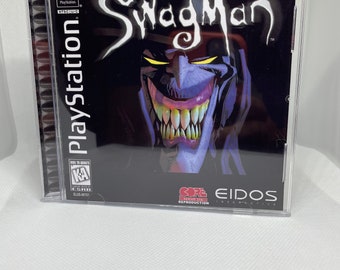 May include: A PlayStation game case with a black background and a purple and white cartoon character with a large grin and sharp teeth. The game title is "Swag Man" and the ESRB rating is "KA" for Kids to Adults. The game is published by Eidos Interactive.
