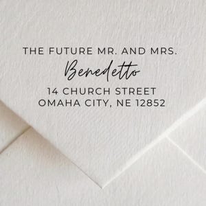 May include: A white envelope with the text "THE FUTURE MR. AND MRS." above the name "Benedetto" in cursive. Below is the address: 14 CHURCH STREET, OMAHA CITY, NE 12852. The envelope is folded, creating a textured surface.