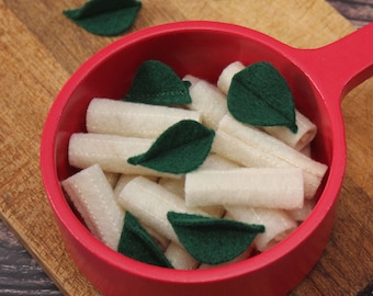May include: A red pot filled with white felt pasta and green felt leaves. The pot has a wooden handle.