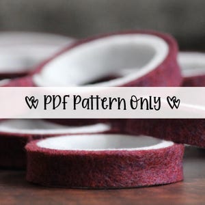May include: Close-up of several rolls of burgundy washi tape with white interiors. The text "PDF Pattern Only" is displayed across the image. The tape has a textured, felt-like appearance, suggesting a craft or DIY project.