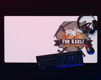 May include: A white rectangular gaming mouse pad with the text "FOR KARL!" and a beer-themed graphic. A black keyboard, mouse, and headset are arranged on the pad, with a gradient background.