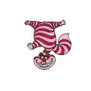May include: A pink and red striped Cheshire Cat from Alice in Wonderland, with a wide grin, is hanging upside down.