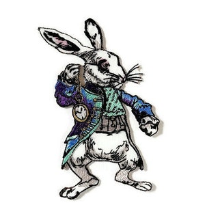 Pode incluir: Coelho branco com roupa azul e verde segurando um relógio de bolso. O coelho é bordado com detalhes precisos e é um personagem caprichoso.