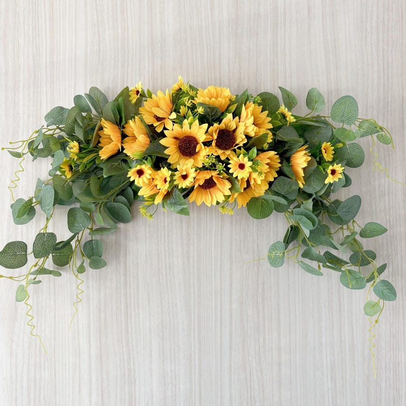 May include: A sunflower garland with yellow and green flowers and leaves. The garland is made of artificial flowers and is perfect for decorating a home or event.