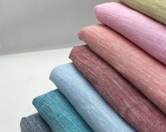May include: A stack of eight fabric swatches in various colors, including teal, light blue, pink, and beige. The fabric has a subtle texture and a slightly wrinkled appearance.