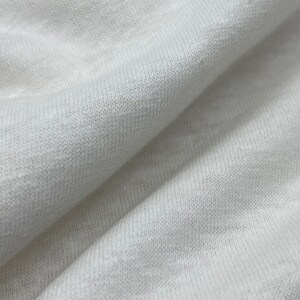 May include: Close-up of a white knitted fabric with a textured surface.